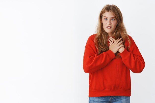 Retrato de mujer sorprendida hasta el fondo del alma presionando las manos al corazón mirando interrogado y asombrado