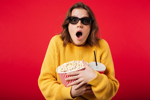 Retrato de una mujer sorprendida en gafas de sol con palomitas de maíz