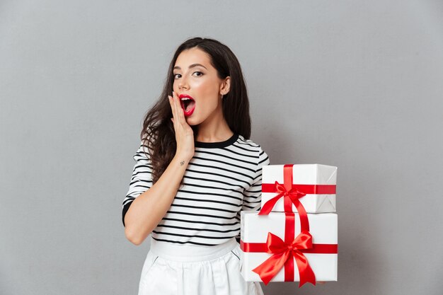 Retrato de una mujer sorprendida con pila de cajas de regalo