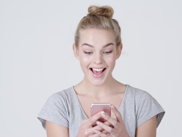 Retrato de una mujer sorprendida con teléfono móvil en las manos - en el estudio