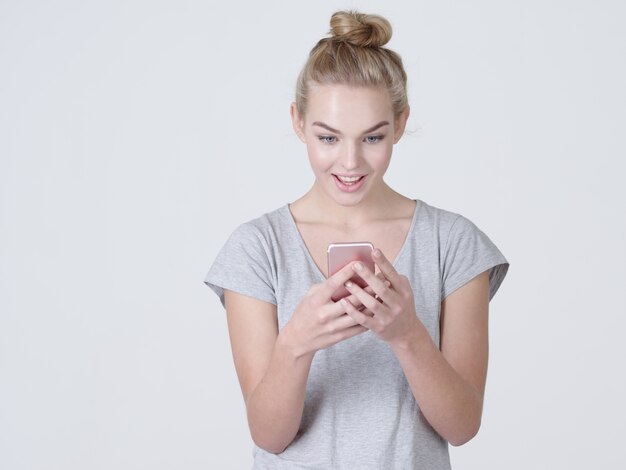 Retrato de una mujer sorprendida con teléfono móvil en las manos - en el estudio