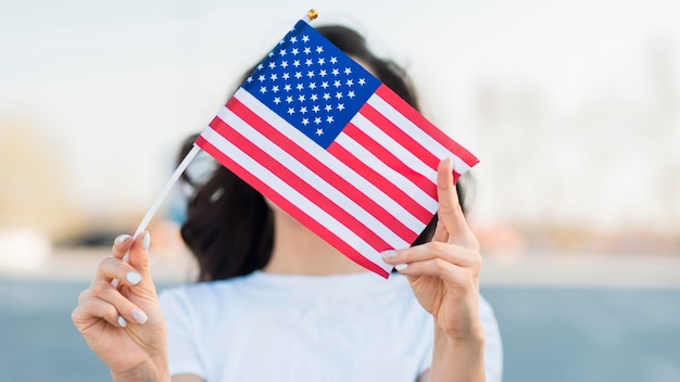 Retrato de mujer sosteniendo la bandera de Estados Unidos sobre la cara