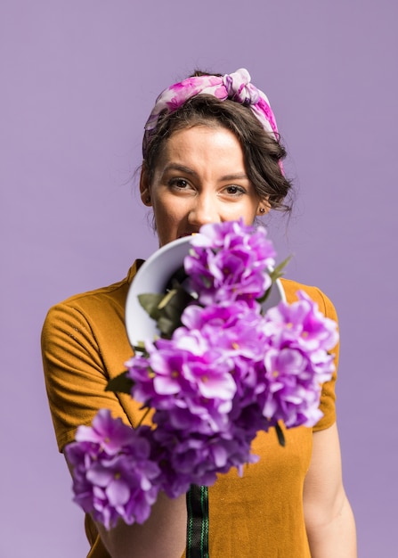 Retrato de mujer sosteniendo delante de su megáfono y flores
