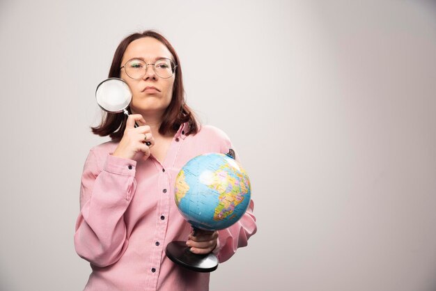 Retrato de mujer sosteniendo una lupa y un globo terráqueo. Foto de alta calidad