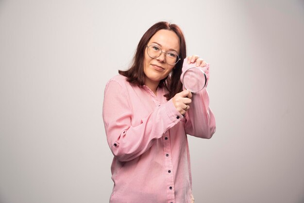 Retrato de mujer sosteniendo una lupa sobre un fondo blanco. Foto de alta calidad