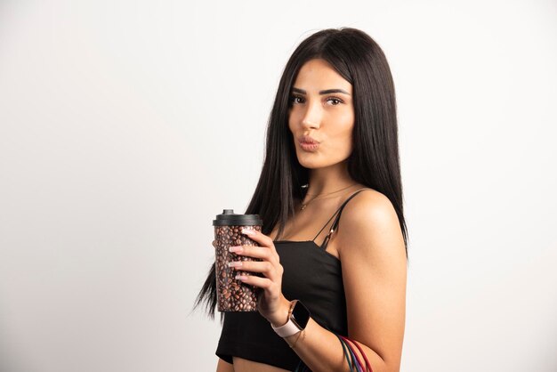 Retrato de mujer sosteniendo una taza de café sobre fondo beige. Foto de alta calidad