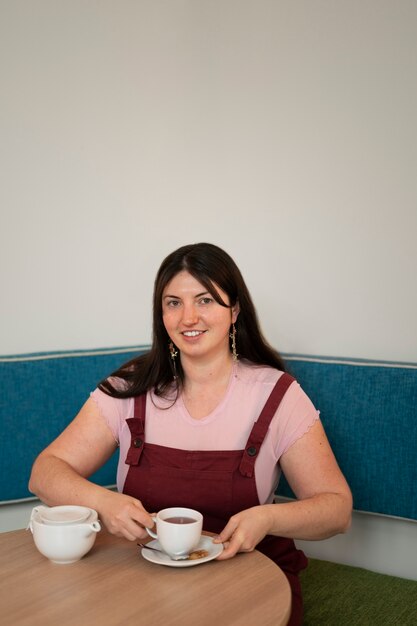 Retrato de mujer de talla grande disfrutando de una bebida en un restaurante