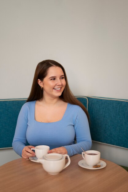 Retrato de mujer de talla grande disfrutando de una bebida en un restaurante