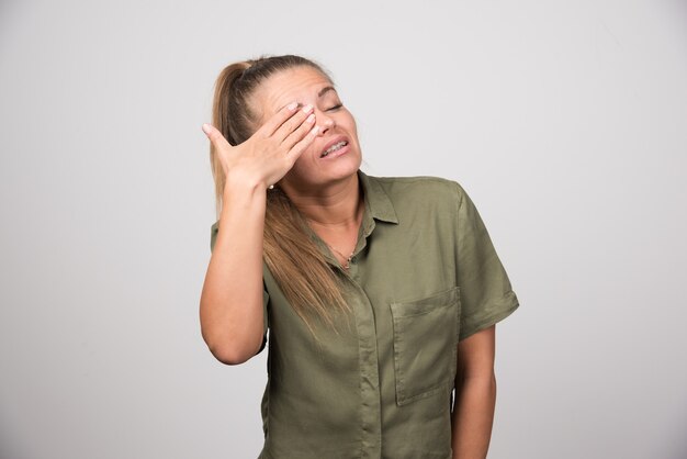 Retrato de mujer tapándose el ojo a causa del dolor.