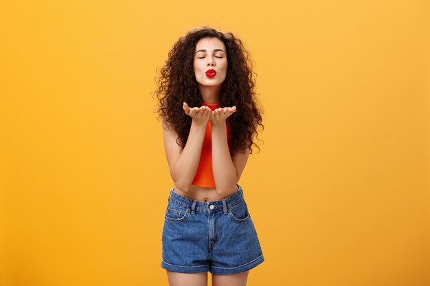 Retrato de mujer tierna encantadora sensual y alegre con lápiz labial rojo peinado rizado y t ...