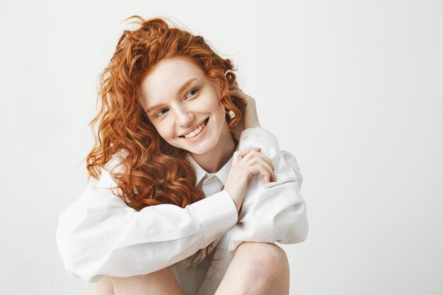 Retrato de mujer tierna jengibre tierna con pelo rizado sonriendo.