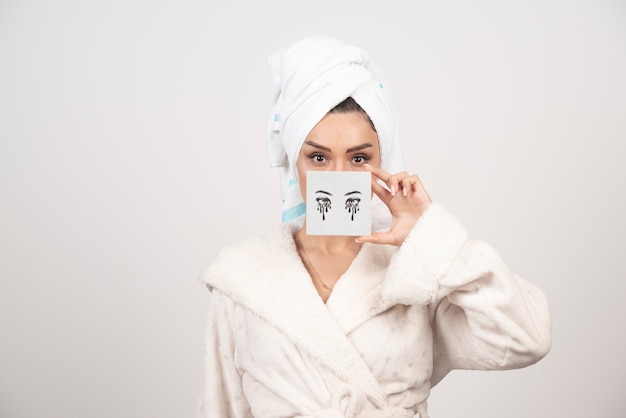 Retrato de mujer en toalla blanca con paleta de sombra de ojos