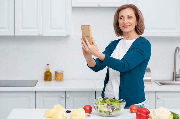 Retrato de mujer tomando un selfie en la cocina