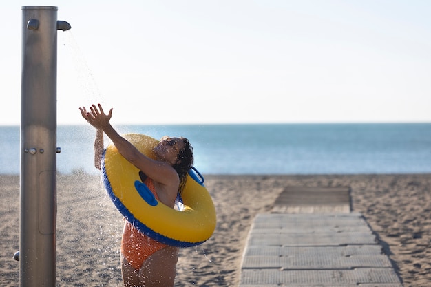 Foto gratuita retrato, de, mujer, tomar, un, ducha, en la playa