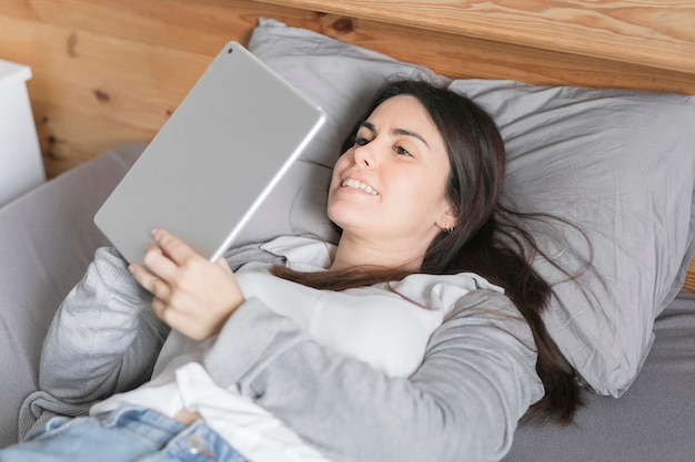 Retrato de mujer trabajando en tableta en la cama