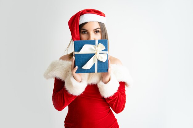 Retrato de mujer en traje de Papá Noel que oculta la cara detrás de la caja