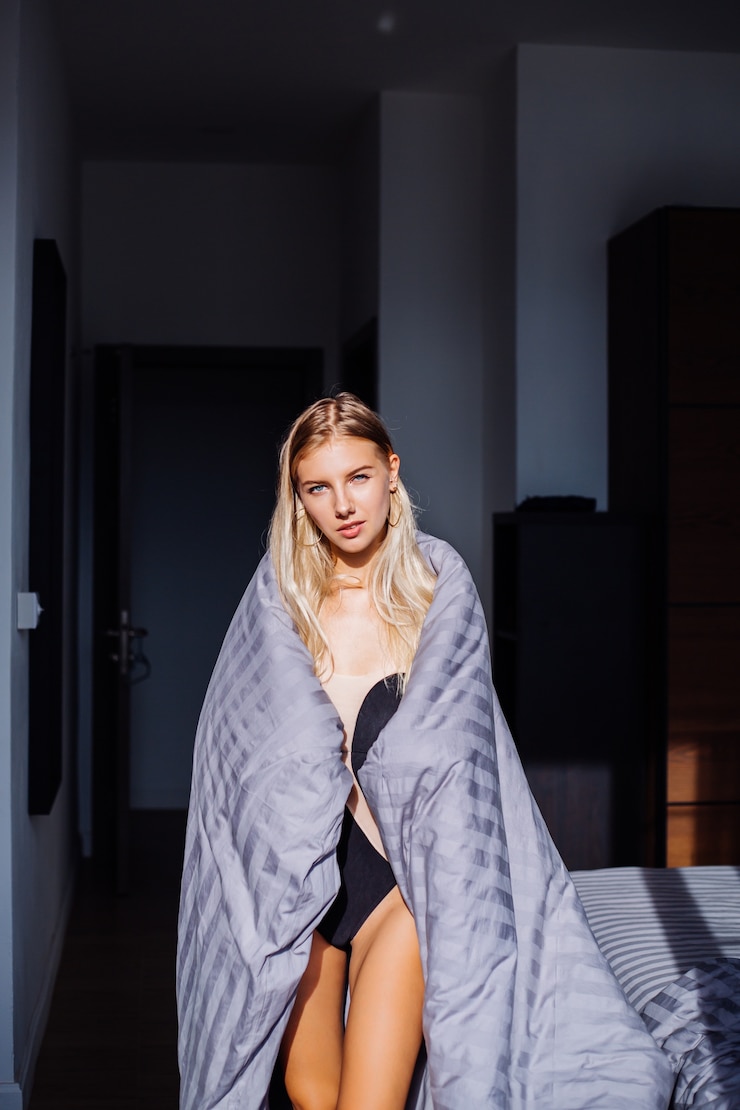 Foto gratuito retrato de mujer tranquila feliz en el dormitorio en manta de rayas gris y cuerpo negro y beige, ropa de dormir en casa