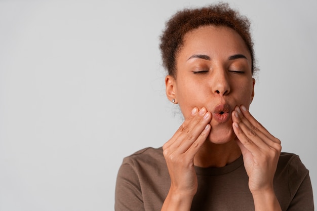 Foto gratuita retrato de mujer tratando de masaje facial de yoga para mantenerse joven