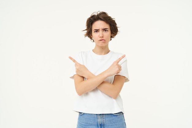 Foto gratuita retrato de una mujer triste y con el ceño fruncido apuntando hacia un lado tomando una decisión compleja y difícil elección aislada