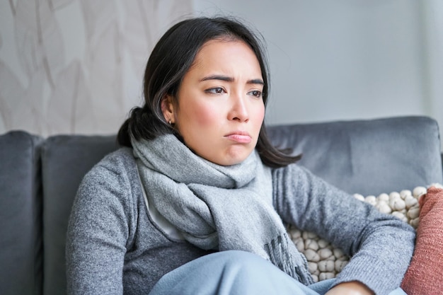 Foto gratuita retrato de una mujer triste que se siente mal usando ropa abrigada y bufanda en su casa sin calefacción