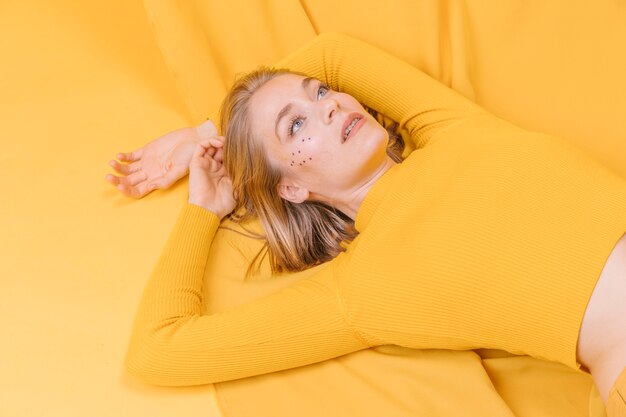 Retrato de mujer tumbada en un escenario amarillo