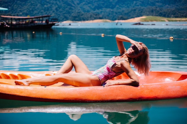 Retrato de mujer turista caucásica joven en forma en bikini relajante en kayak en el hermoso lago de Tailandia. Mujer de vacaciones disfrutando de un día soleado.