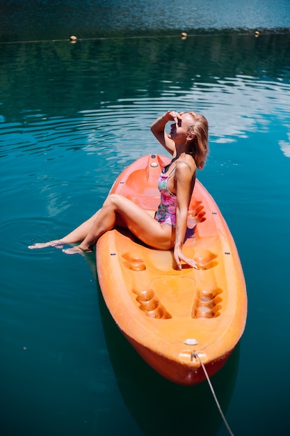 Retrato de mujer turista caucásica joven en forma en bikini relajante en kayak en el hermoso lago de Tailandia. Mujer de vacaciones disfrutando de un día soleado.