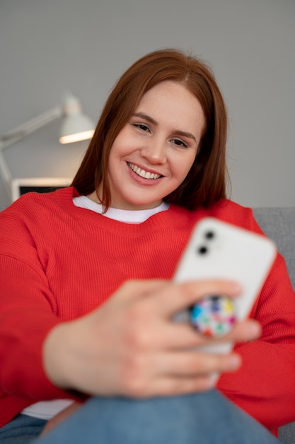 Retrato de mujer usando un teléfono inteligente en casa con toma de corriente