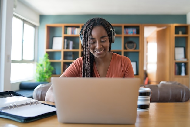 Retrato de una mujer en una videollamada con una computadora portátil y auriculares mientras trabaja desde el concepto de hogar