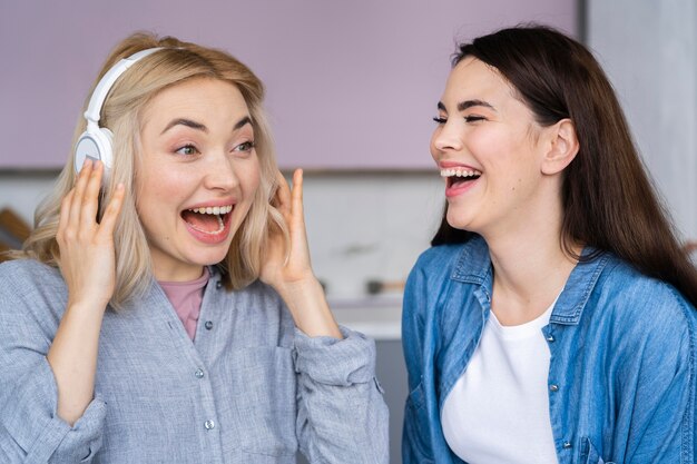 Retrato de mujeres felices riendo y escuchando música con auriculares