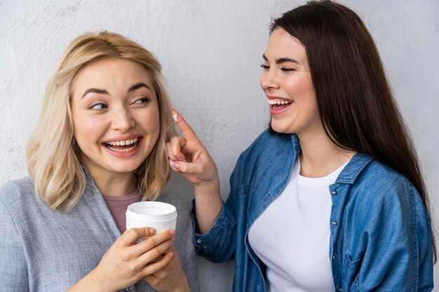 Retrato de mujeres felices riendo y jugando con crema hidratante