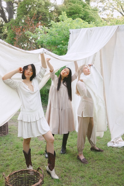 Retrato de mujeres hermosas en el jardín, colocando y sosteniendo el paño blanco en el vestido blanco durante el día.