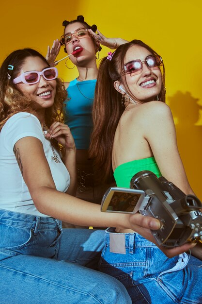 Retrato de mujeres jóvenes en el estilo de moda de la década de 2000 posando con cámara