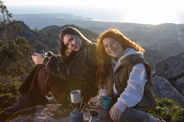 Retrato de mujeres jóvenes felices bebiendo té en las montañas
