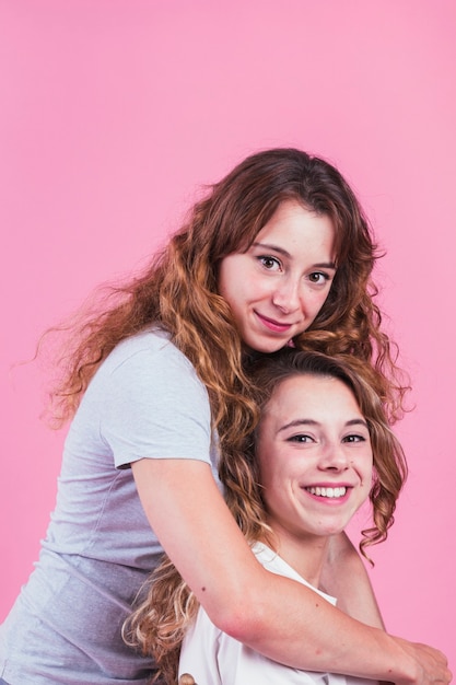 Retrato de mujeres jóvenes sonrientes contra el fondo rosado