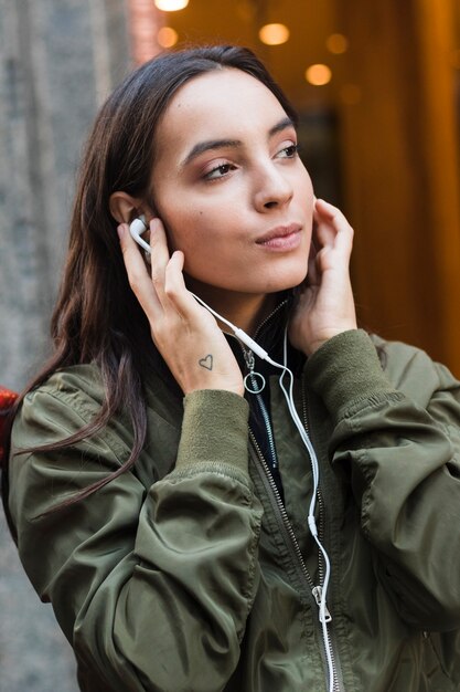 Retrato de una música que escucha de la mujer joven en el auricular