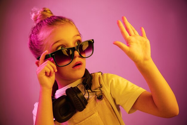 Retrato de neón de niña asustada con auriculares disfrutando de la música.