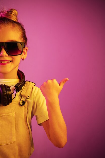 Retrato de neón de niña con auriculares disfrutando de la música. Estilo de vida de los jóvenes, las emociones humanas, la infancia, el concepto de felicidad.