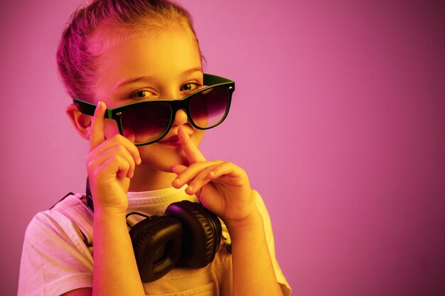 Retrato de neón de niña con auriculares disfrutando de la música y pidiendo silencio.