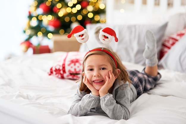 Retrato de niña acostada en la cama en Navidad