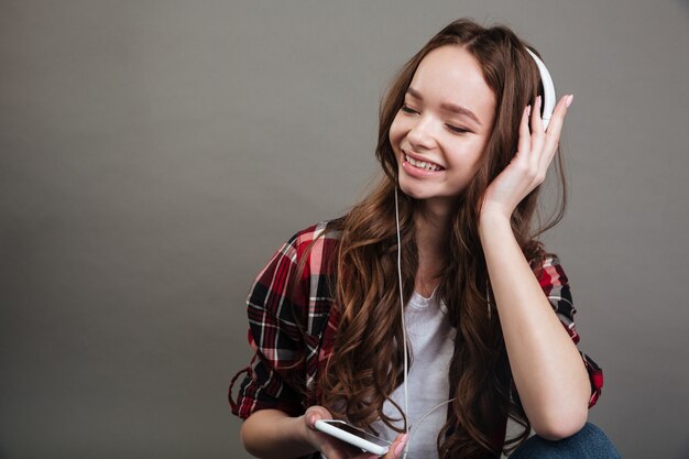 Retrato de una niña adolescente sonriente disfrutando de la música con auriculares