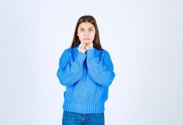 Retrato de niña adolescente en suéter azul de pie con expresión triste.