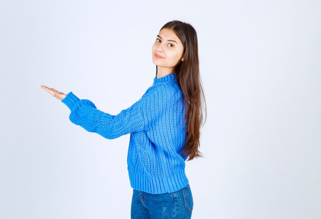 Retrato de niña adolescente en suéter azul de pie y mostrando el espacio abierto.