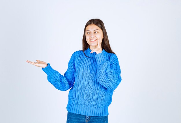 Retrato de niña adolescente en suéter azul de pie y mostrando el espacio abierto.