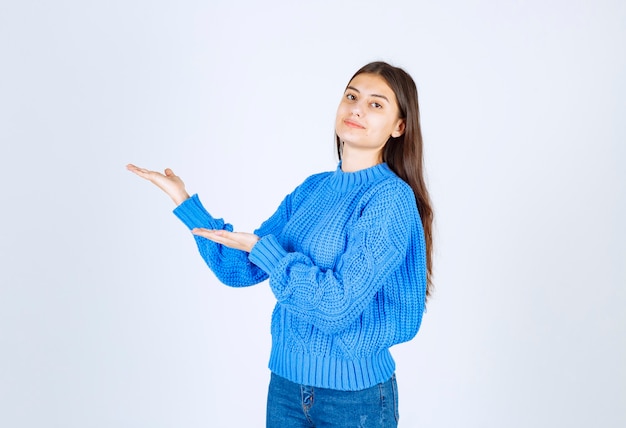 Retrato de niña adolescente en suéter azul de pie y mostrando el espacio abierto.