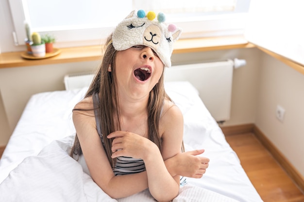 El retrato de una niña adorable subió a su cama en la mañana soleada