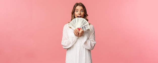 Retrato de niña afortunada emocionada con cabello rubio vestido blanco ganando dinero recibe premio en efectivo big lott