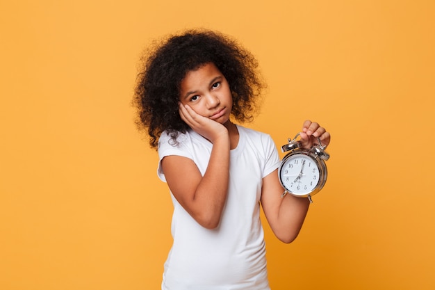 Retrato de una niña africana cansada con despertador