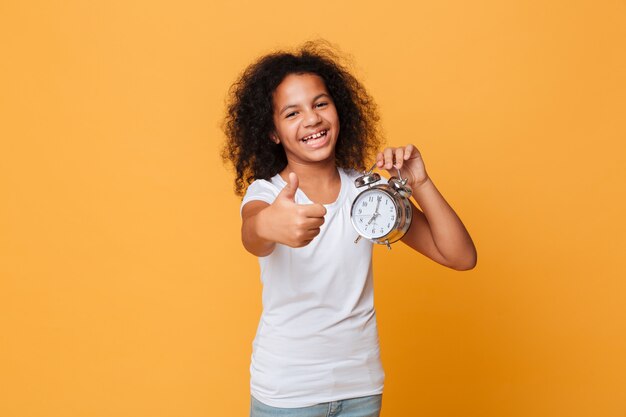 Retrato de una niña africana feliz con despertador