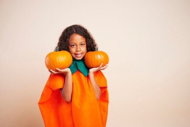 Retrato de niña africana sosteniendo dos calabazas de halloween